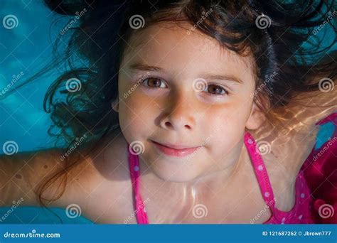 Маленькая девочка с большими глазами Брайна плавает в бассейн с
