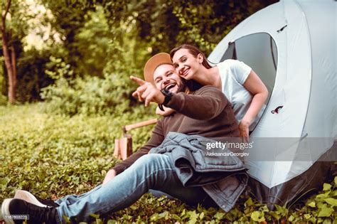 Couple Laughing And Pointing During Camping Trip In Woods High Res