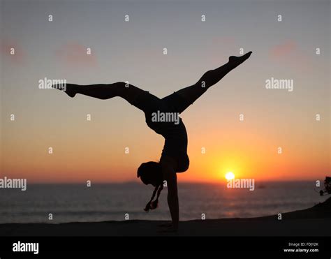 Silhouette Of A Woman Doing Handstand With Legs Apart On The Beach