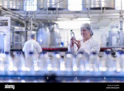 trabajadora inspeccionando la botella de agua en la línea de producción en la fábrica de agua de