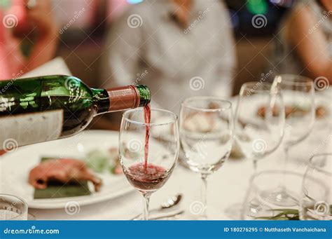 waitress is pouring red wine in glasses for wine tasting event on the table in restaurant