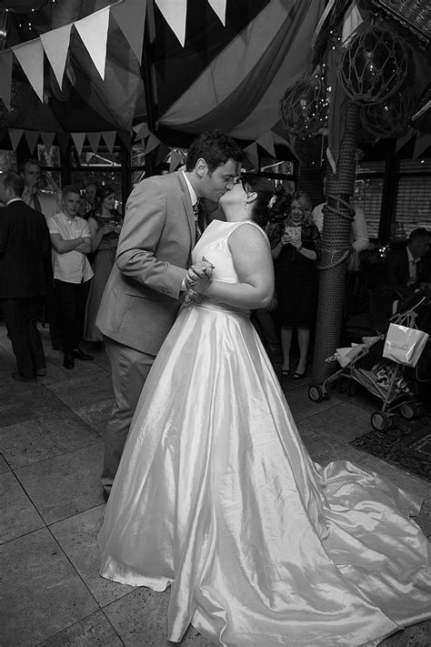 A Bride And Groom Sharing A Kiss On The Dance Floor At Their Wedding Reception In Black And White