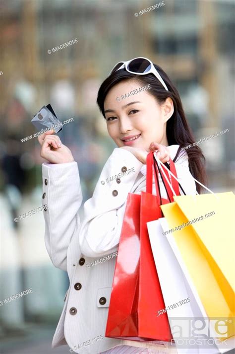Young Woman Holding Shopping Bags Over Shoulder With Two Bank Cards