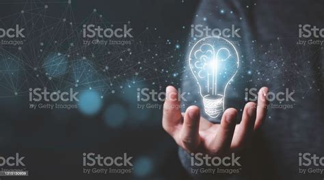 Businessman Holding Half Of Virtual Lightbulb And Brain On Blue Bokeh
