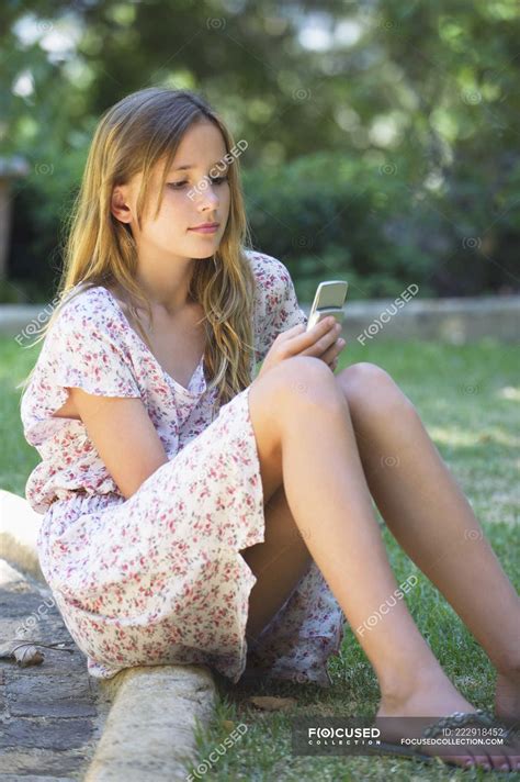 Cute Teenage Girl Using A Mobile Phone In Garden Text Messaging Leisure Stock Photo