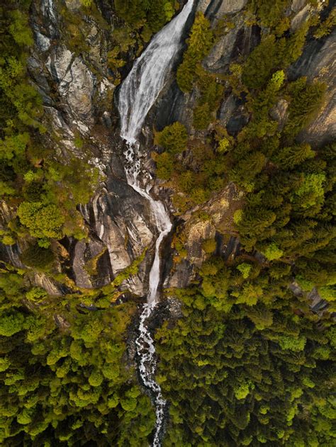 Aerial View Of A Steep Majestic Waterfall Hidden By The Forest In Val