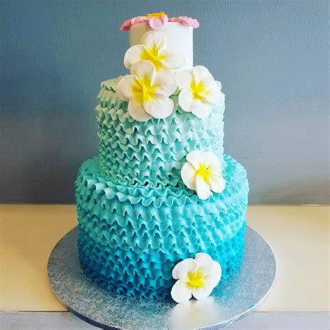 Turquoise Ombre Ruffle Cake With Yellow And White Hibiscus Flowers