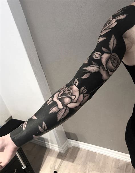 This tattoo includes a black and white inked lion's face with two roses below the lion. Black Ink Sleeve With White Roses