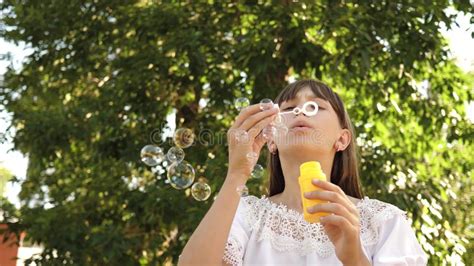 Happy Girl Blowing Beautiful Soap Bubbles In The Park In Spring Summer And Smiling Slow Motion