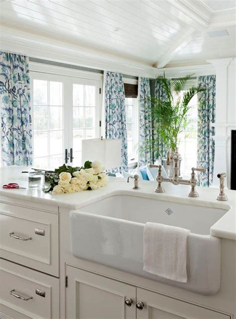 A White Sink Sitting Under A Window Next To A Window Covered In Blue