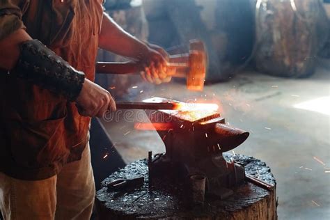 Blacksmith Working Metal With Hammer On The Anvil In The Forge Stock