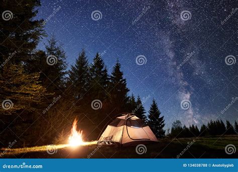 Night Camping In Mountains Tourist Tent By Campfire Near Forest Under
