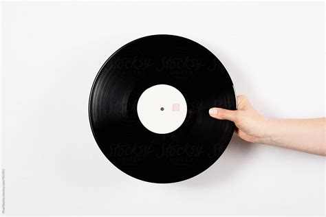 Hand Holding Vinyl Record Over White Background By Stocksy