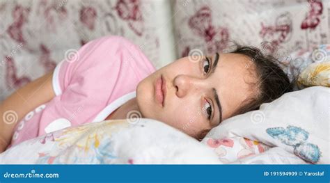 Teenage Brunette Wakes Up Looking Straight And Lying In Bed Stock Image