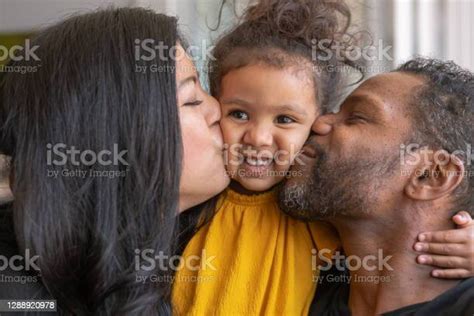Smiling Preschool Age Girl Being Kissed By Her Adoring Parents Stock