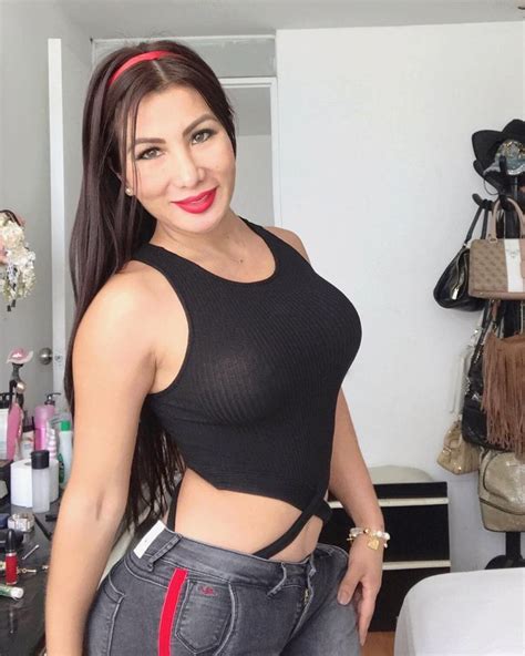 A Woman In Black Top And Jeans Posing For The Camera With Her Hands On
