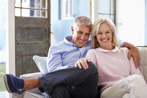 Portrait Of Smiling Mature Couple Sitting On Sofa At Home The Global Beauty Group
