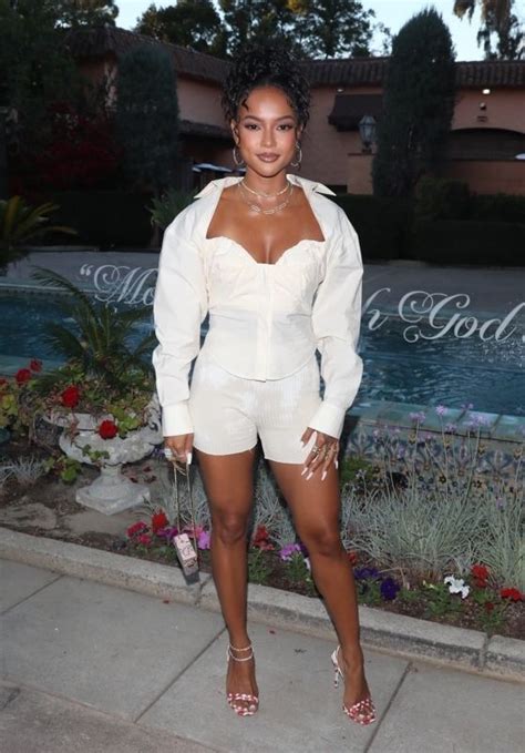 A Woman Standing In Front Of A Fountain Wearing High Heels And A White