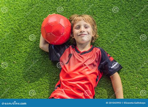 Little Cute Kid Boy In Red Football Uniform Playing Soccer Football On