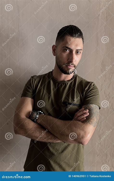 Handsome Young Man With A Stylish Hairstyle And Stubble Beard Stands On