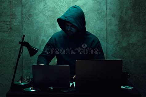 Anonymous Hacker Wearing Face Mask Working On Computer In Dark Room