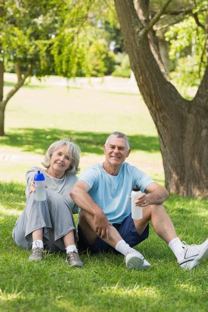 Premium Photo Mature Couple Sitting With Water Bottles At Park