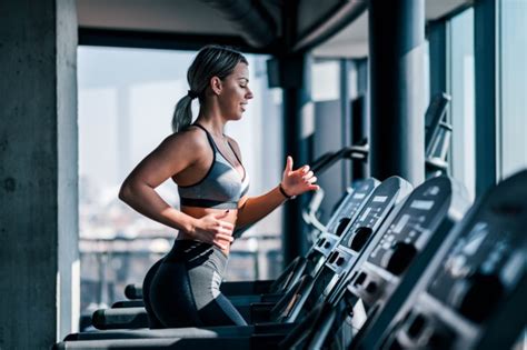 Side View Of Beautiful Muscular Woman Running On Treadmill Workout