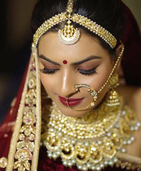 A Woman In A Red And Gold Outfit With Jewelry On Her Face Wearing A Head Piece