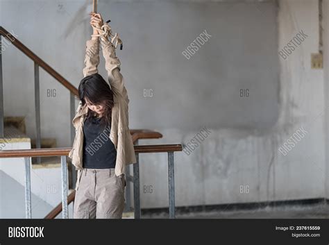 Woman Kidnapped By Criminals Hanging With Hands Tied Up With Rope In Abandoned Buildings Image