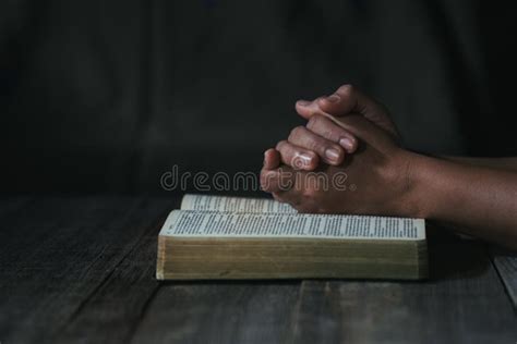 Hands Folded In Prayer On A Holy Bible In Church Concept For Faith