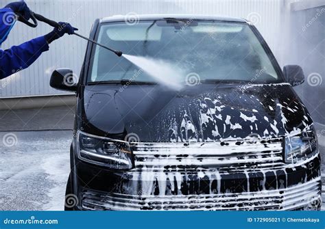 Worker Cleaning Automobile With High Pressure Water Jet At Car Wash