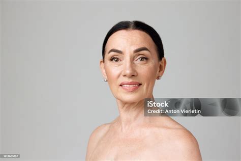 portrait of smiling beautiful dark heared mature woman with bare shoulders looking at camera