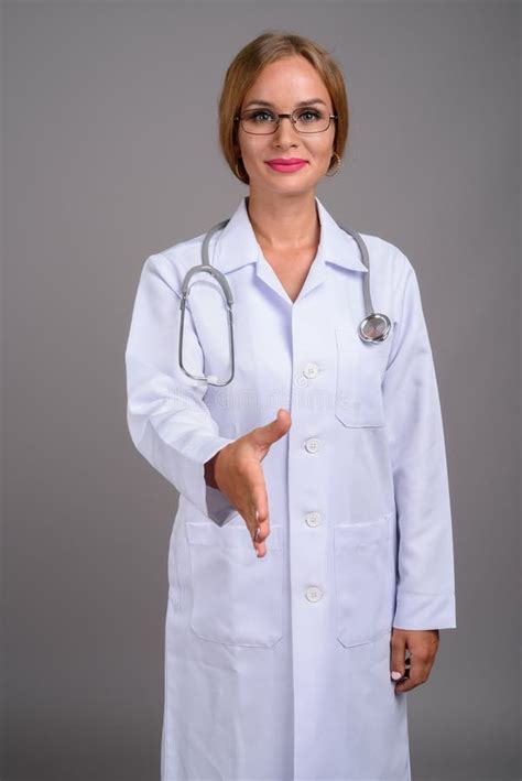 Young Beautiful Woman Doctor With Blond Hair Against Gray Backgr Stock