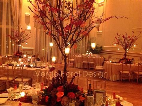 The Centerpiece Is Decorated With Red Flowers And Branches