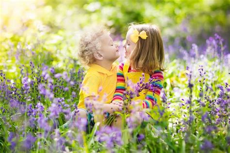 Kids Playing In Blooming Garden With Bluebell Flowers Stock Photo