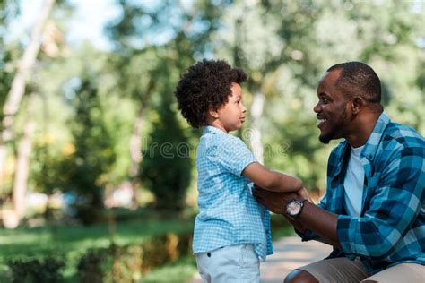 View Of Cheerful African American Father Holding Hands With Son Stock