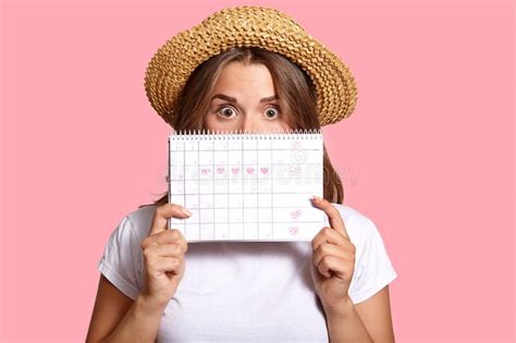 Photo Of Surprised Dark Haired Woman Hides Behind Periods Calendar