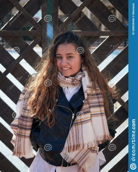 Vertical Shot Of A Young Caucasian Female Posing Against A Wooden Fence