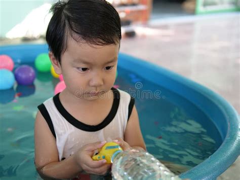Asian Cute Child Boy Playing Water In Blue Bowl With Relaxing Face And