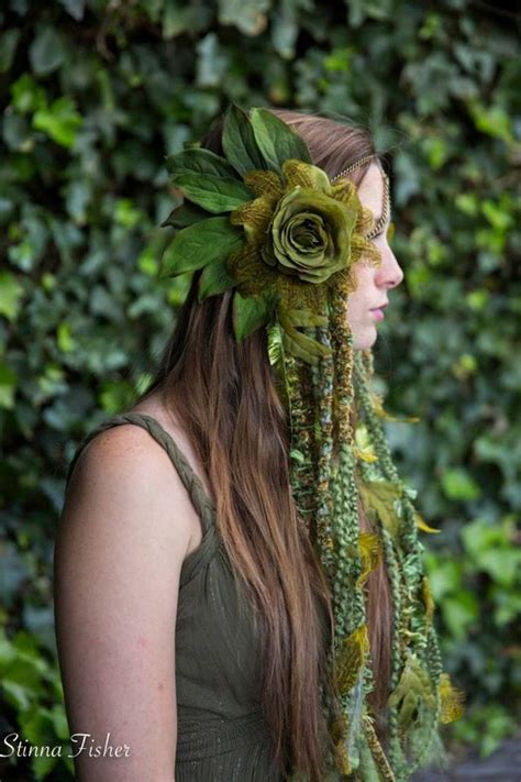 A Woman With Flowers In Her Hair Wearing A Green Head Piece Made Out Of