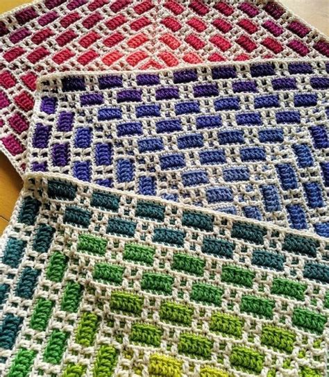 Two Crocheted Squares Are Sitting On A Table Top One Is Multicolored