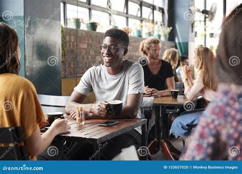 Couple Sitting At Table In Busy Coffee Shop Talking Stock Photo Image