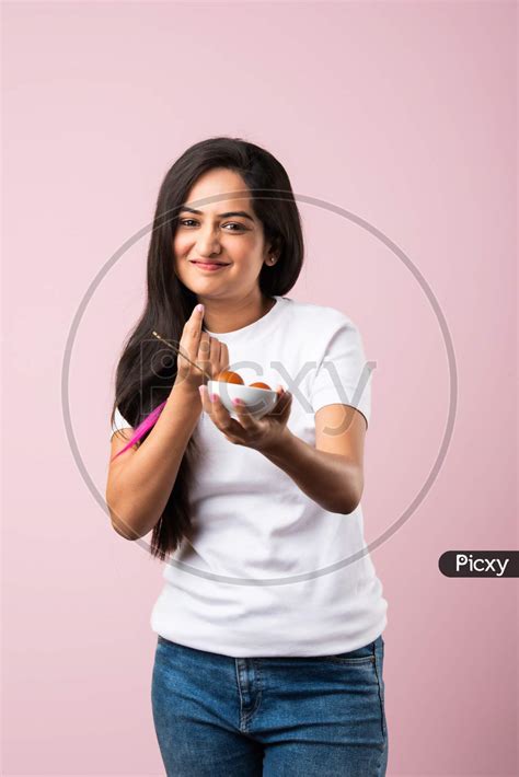 Image Of Indian Asian Pretty Young Woman Eating Gulab Jamun Sweet Food