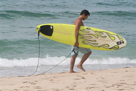 file sufer carrying surfboard along the beach wikimedia commons