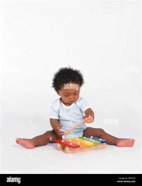 Baby Boy Playing With Xylophone And Beater Sitting On Floor Stock