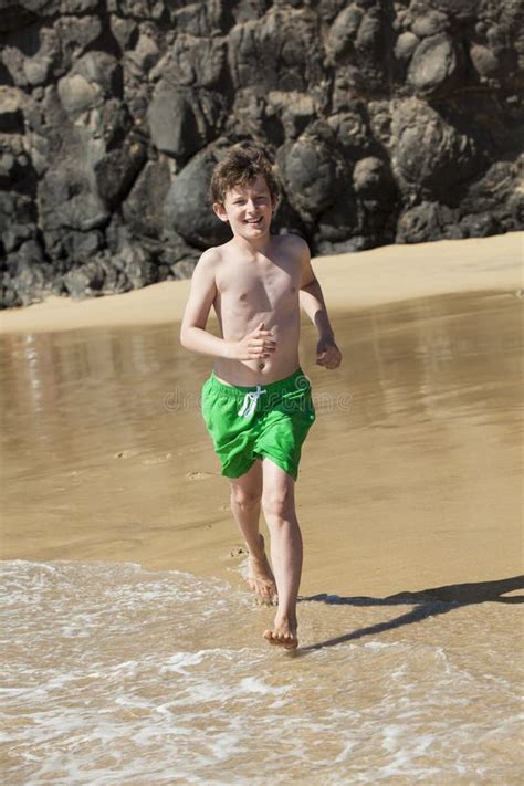 El Muchacho Está Corriendo a Lo Largo De La Playa En Un Día Soleado Imagen de archivo Imagen