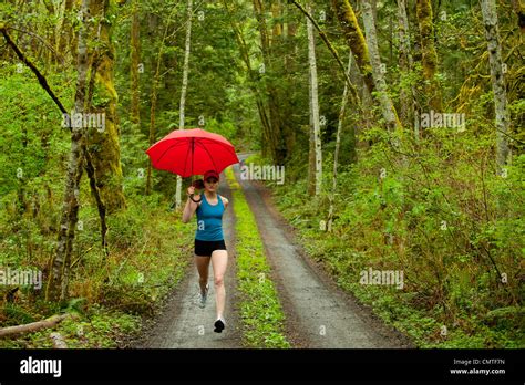 Mixed Race Runner Training On Remote Road With Umbrella Stock Photo Alamy