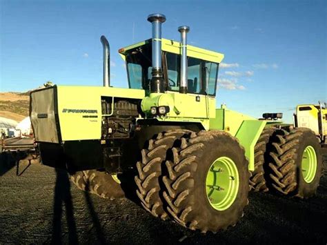 A Large Green Tractor Parked On Top Of A Dirt Field