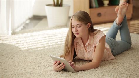 Beautiful Young Woman Lying On Floor Using Touchpad And Smiling Stock