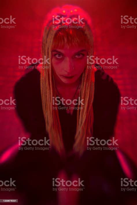 Young Woman On Her Knees With Devilish Look In Her Eyes Red Lights